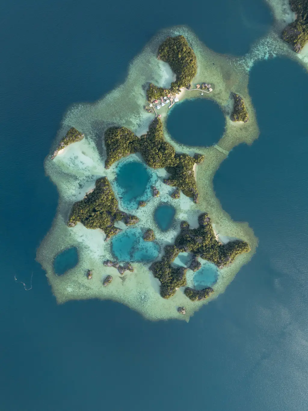 A cluster of deep blue pools scattered across a shallow reef platform