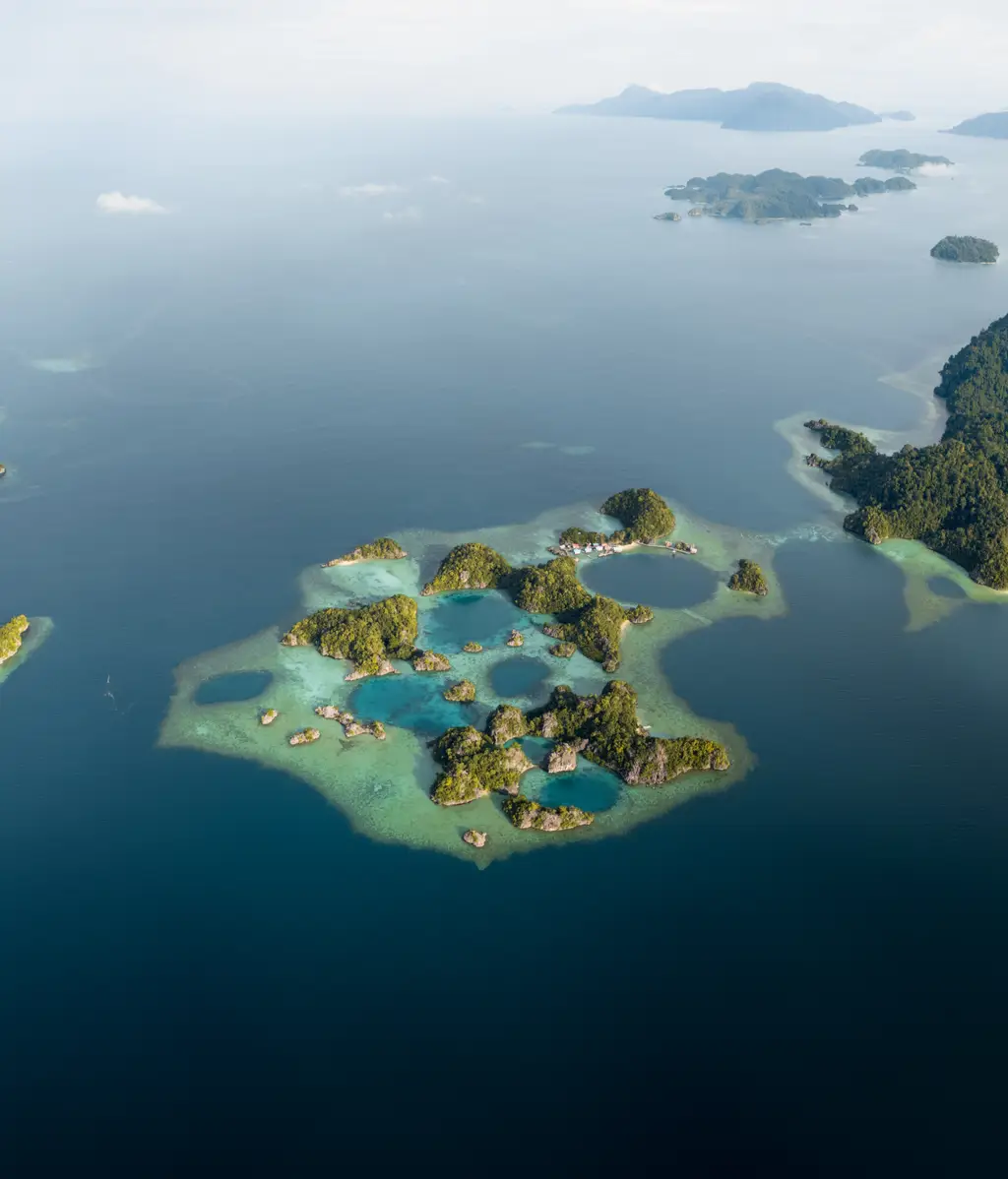 A wide panorama of the archipelago, reef and islets running to a distant ridgeline