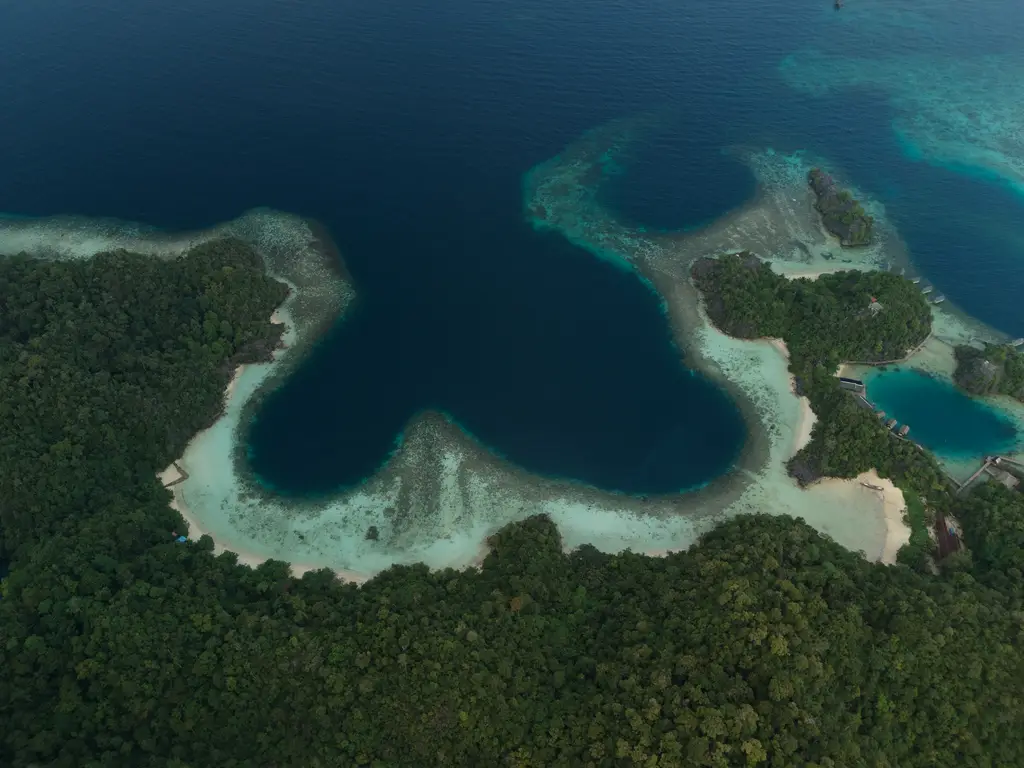 A deep blue channel curving between forested karst ridges