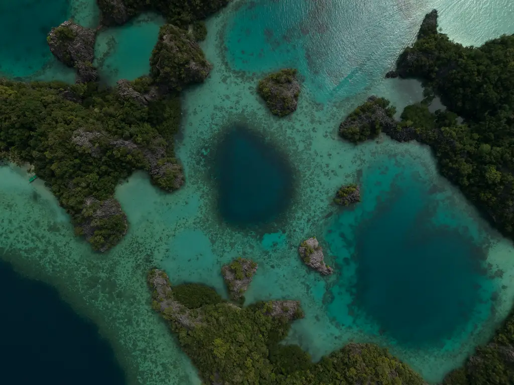 Blue and turquoise pools set into a shallow reef between low limestone islets