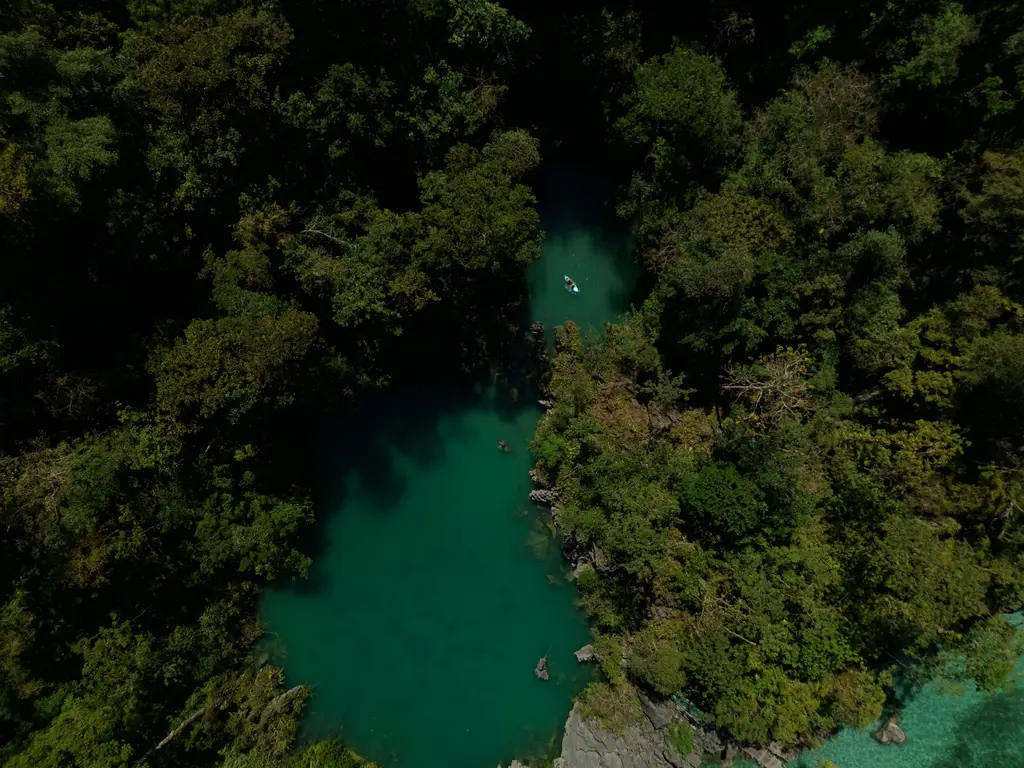 A narrow green lagoon winding between densely forested limestone slopes