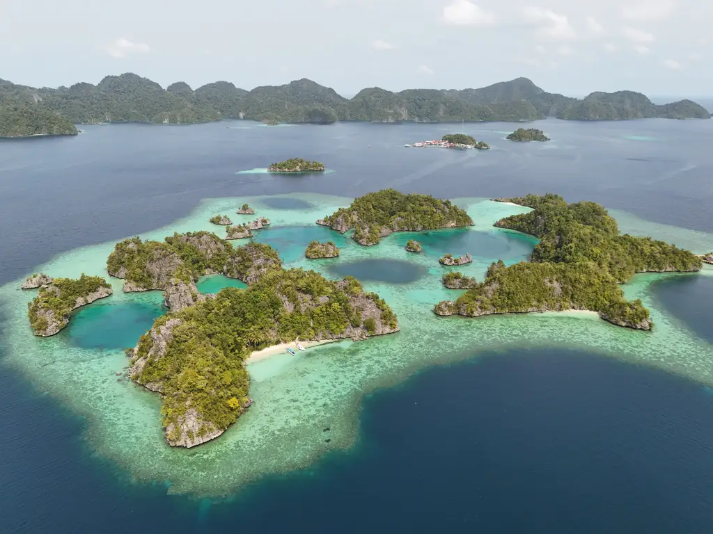 A wide view across the archipelago, green islets in turquoise shallows with open sea beyond