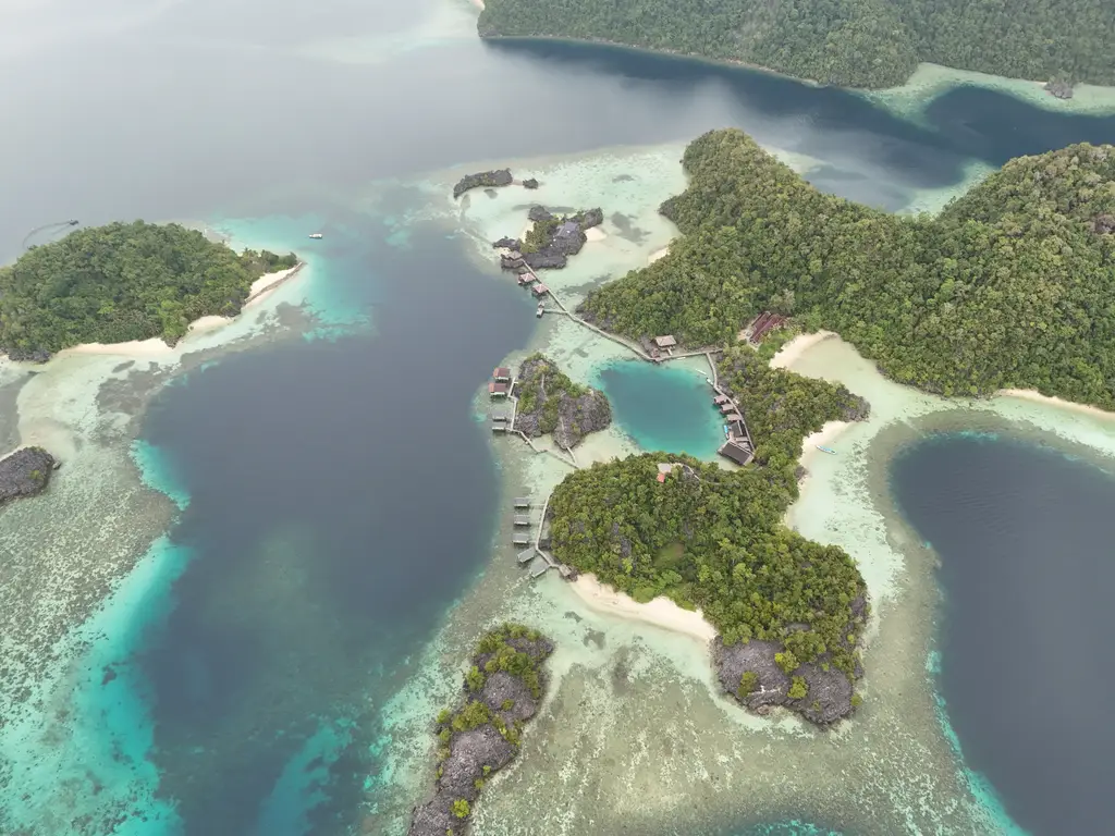 Stilt buildings and a walkway between sandbars and lagoons, with reef visible through the shallows