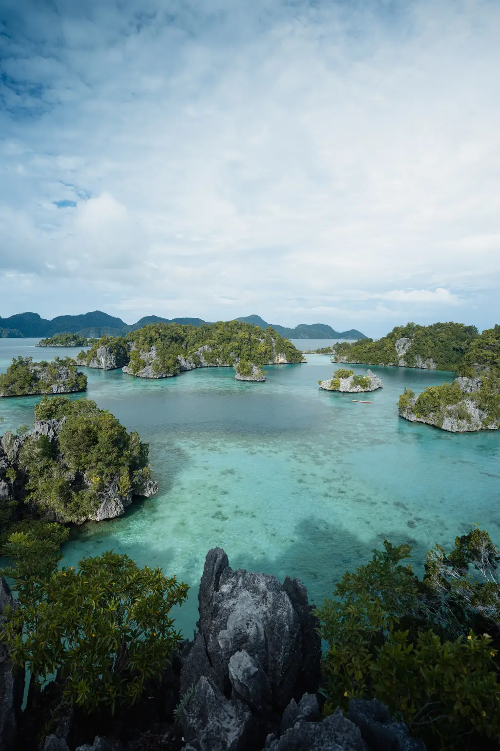 Karst islets standing in calm pale-blue water under a wide open sky